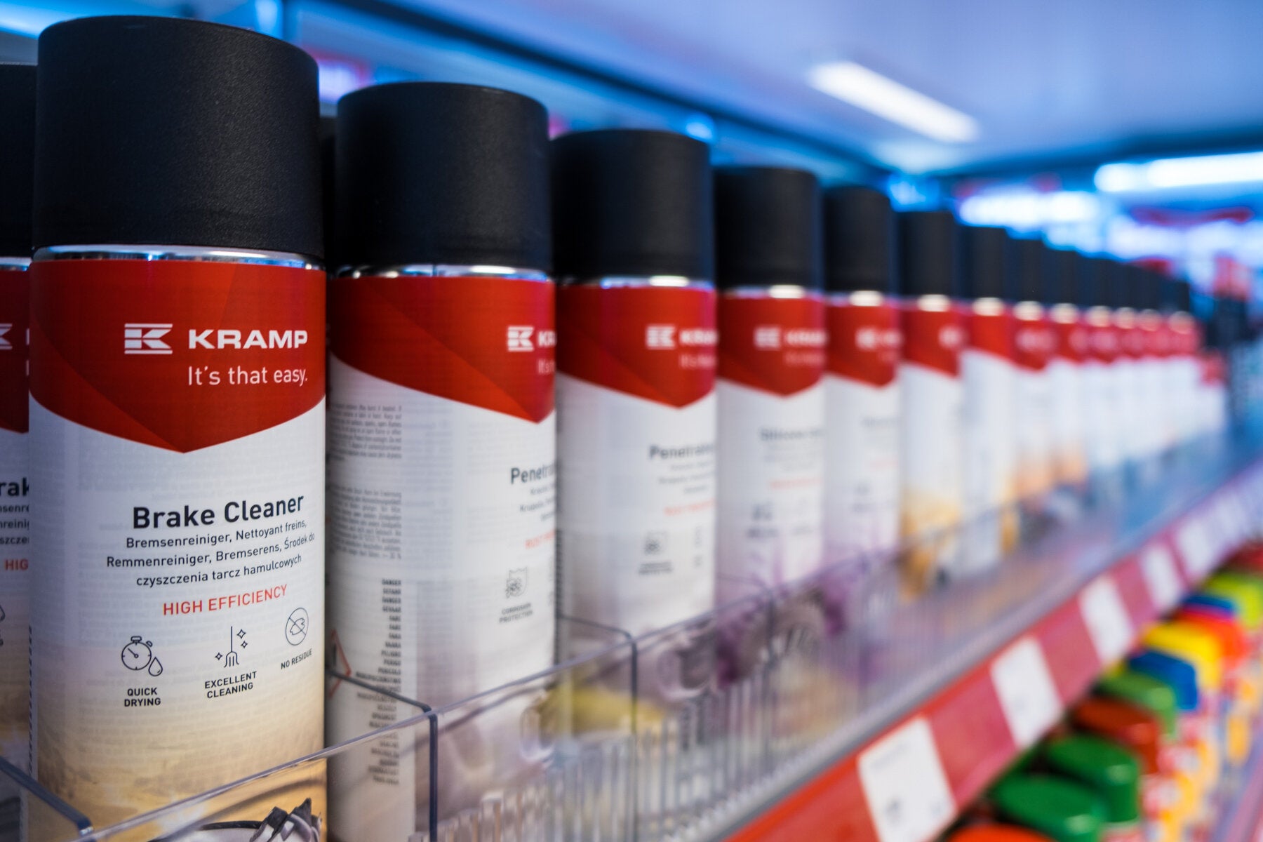 Hylle med Kramp bremserens spraybokser i en butikk. Rød og hvit etikett med "It's that easy." i tekst. Flere spraybokser står oppstilt på rad for salg.